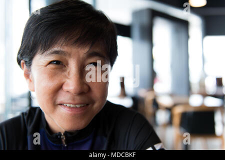 Senior asiatische Frau mit Kaffee in Trikot Stockfoto