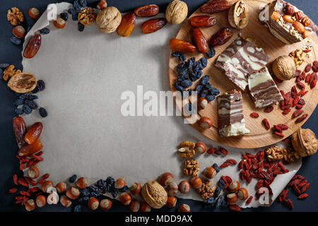 Mehrere Stücke von halvah, Nüsse und getrocknete Früchte essen Rahmen auf Papier Hintergrund mit Kopie Platz für Text Messaging. Ansicht von oben, kopieren Raum Stockfoto