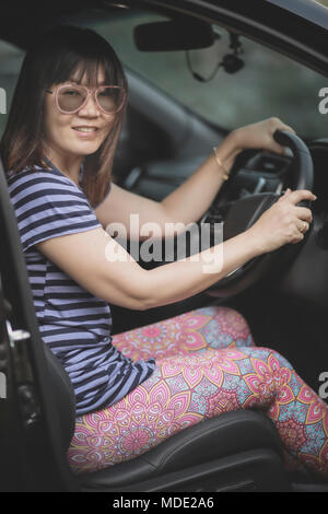 Schöne asiatische Frau sitzt auf dem Fahrersitz toothy Lächeln Stockfoto