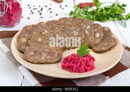 Hausgemachte diätetische Wurst aus der Leber auf eine weiße Holztisch. Wurst in Stücke geschnitten auf einer Platte mit Meerrettichsauce. Stockfoto