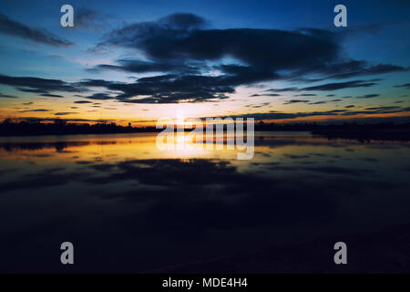 Schöne bunte orange Himmel bei Sonnenuntergang auf dem See. Himmel bei Sonnenuntergang über dem See, Thailand. Stockfoto