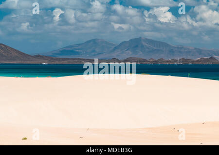 Blick auf den berühmten Sanddünen von Corralejo am Strand Playa Larga in Fuerteventura, Spanien mit Lanzarote im Hintergrund. Stockfoto