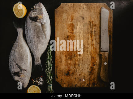 Blick von oben auf die beiden dorado Fisch mit Zitrone und Rosmarin auf Schneidebrett. Stockfoto