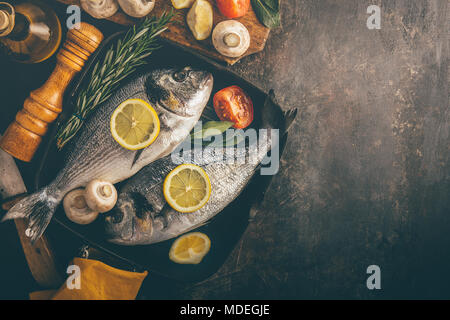 Blick von oben auf die Dorado mit Gemüse in der Backform auf unebenem Untergrund. Stockfoto