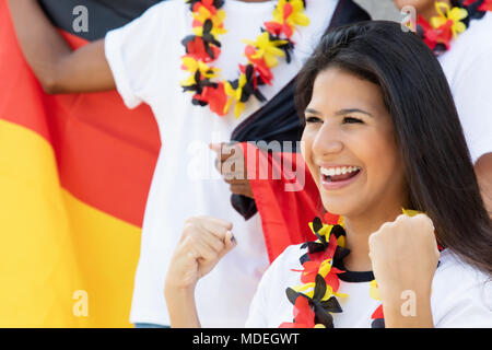 Jubelnde deutsche Fußball-Fan im Stadion mit anderen Fans und Deutsche Flagge Stockfoto