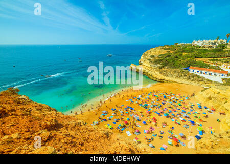 Luftaufnahme von Golden-farbigen Klippen von Praia De Benagil in der Nähe von Lagoa, Algarve, Portugal, Europa. Touristen Sonnen in berühmten Benagil Strand bekannt für eine beeindruckende Höhle, bekannt als Algar De Benagil. Stockfoto