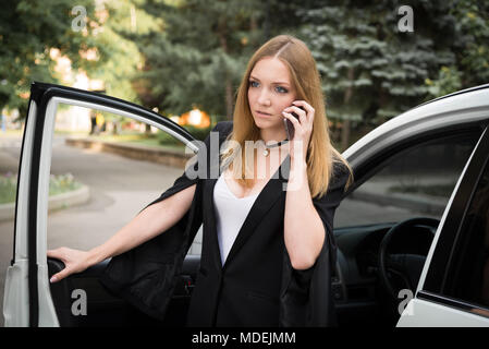 Blonde Mädchen in der Nähe ein weißes Auto, am Telefon zu sprechen Stockfoto