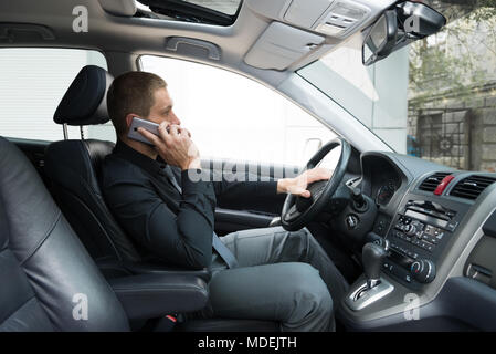 Der Mann im Auto ist, am Telefon zu sprechen Stockfoto
