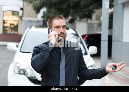 Bärtiger Mann emotional sprechen über das Telefon in der Nähe des Auto Stockfoto