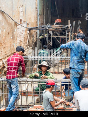 Vietnamesische Arbeiter auf einer kleinen Baustelle Festlegung Ziegel ein Tun Schalung für den Keller eines Gebäudes in Ho Chi Minh City, Vietnam. Stockfoto