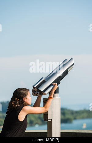 Junge Mädchen in schwarzen T-Shirt ist durch eine Münze zu schauen betrieben Fernglas am Ufer des Bodensees. Stockfoto