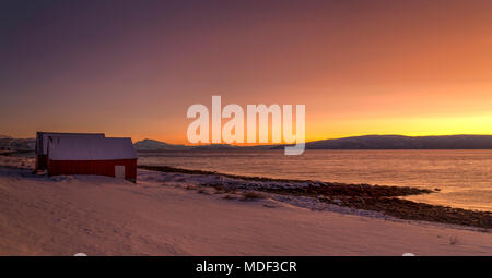 Bootshäuser am Ufer der Insel Kvaløya in Nordnorwegen im Winter. Stockfoto