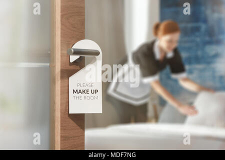 Ein hausmädchen Reinigung ein Zimmer in den Hintergrund und die Tür mit einem Schild an der Vorderseite Stockfoto