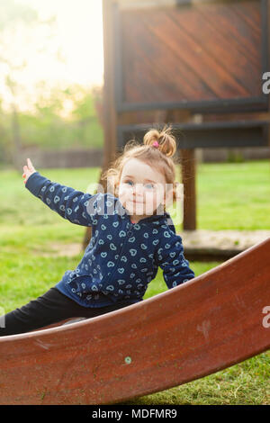 Little Baby Mädchen spielt gerne im Park im Freien in der Feder gegen die Hintergrundbeleuchtung. Stockfoto