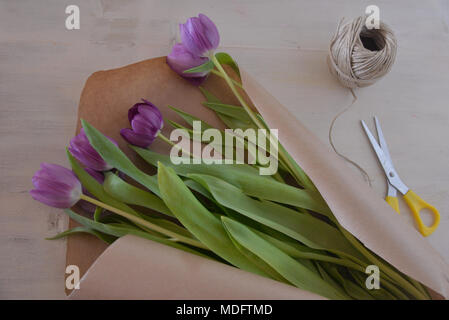 Blumenstrauß aus Tulpen, braunem Papier, Schnur und Schere Stockfoto