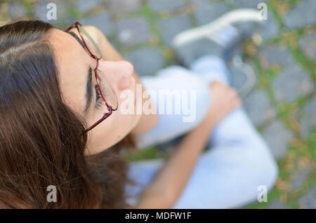 Ansicht von oben ein Mädchen sitzt auf dem Bürgersteig Stockfoto