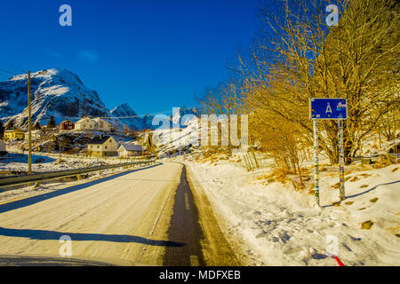 Henningsvær, Norwegen - 04 April, 2018: Im freien Blick auf informative Zeichen mit Holzhäusern auf der einen Seite der Strasse mit Schnee eines typischen kleinen Dorf in Lofoten abgedeckt Stockfoto