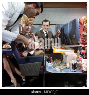 1950er Jahre First Class Flying Airline Service Air Steward Flugzeugkabine für First Class Passagiere 1950er-1960er First Class Air Travel die goldene Ära der Passagierluftfahrt männlicher Passagier raucht Zigaretten Stockfoto