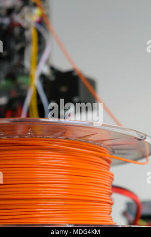 3d-Drucker orange Filament mit Drucker im Hintergrund Stockfoto