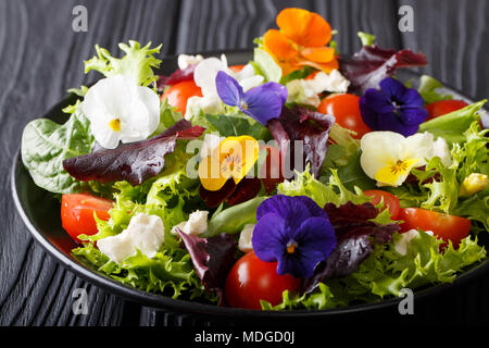 Sommer Salat von essbaren Blüten mit Salat, Spinat, Tomaten und Feta close-up auf dem Tisch. Horizontale Stockfoto