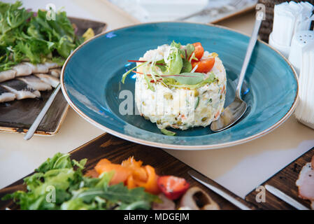 Russische traditionelle Salat Olivier auf blauen Platte Stockfoto