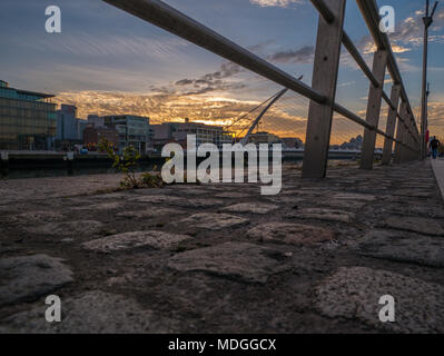 Dublin, Irland - Dublin Kais bei Sonnenuntergang, mit Blick auf den Fluss Liffey und die Samuel Beckett Brücke, die allgemein als die Harfe Brücke bekannt. Stockfoto