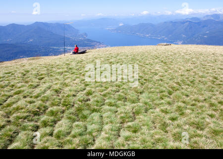 Ein Tourist, der den schönen Blick auf den Lago Maggiore (Lago Maggiore) vom Gipfel des Monte Lema (Mount Lema) aus betrachtet. Veddasca, Italien Stockfoto