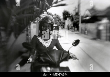 Negombo, Sri Lanka, 13. Dezember 2015: Ein schönes Mädchen sitzt auf einem Motorroller und lächelt. Achtung! Das Bild enthält Granularität und andere artifa Stockfoto