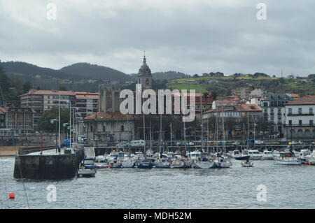 Hafen von Lekeitio mit seinen Booten durch die zeitliche Hugo Im Hintergrund Blick auf die Gebäude der Stadt Presious vertäut. März 24, 2018. Architectu Stockfoto