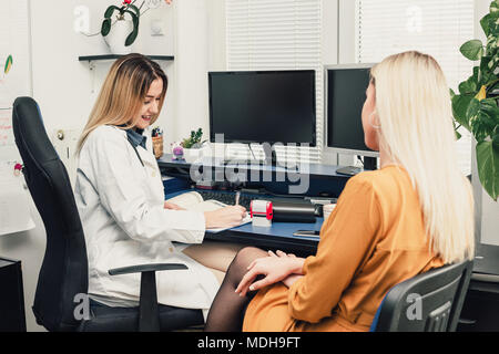 Arzt im Gespräch mit weiblichen Patienten in der Arztpraxis. Gesundheitswesen und Medizinische Konzept Stockfoto