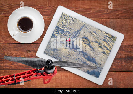 Reiten ein fettes Bike auf einem Desert Trail, die Überprüfung eine Antenne Bild auf einem digitalen Tablette mit einer Tasse Kaffee Stockfoto