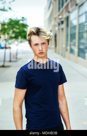 Porträt eines Teenager-Jungen trägt ein blaues T-Shirt und stehen auf einem Bürgersteig in einem städtischen Gebiet; Toronto, Ontario, Kanada Stockfoto