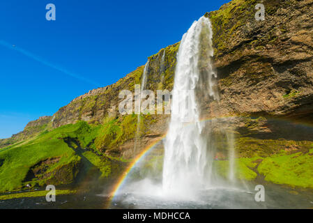 Skogafoss Wasserfall mit blauer Himmel und ein Regenbogen im Nebel ; Island Stockfoto