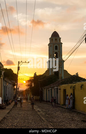 TRINIDAD, Kuba - Januar 25, 2017: Kubaner zu Fuß durch die Straßen mit Kopfsteinpflaster in einem schönen Sonnenuntergang. Im Hintergrund der Turm der Sklaven. Stockfoto