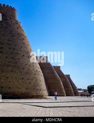 Buchara, Usbekistan - April 2015: Eine Frau schaut auf das riesige Arche Festung in der zum UNESCO-Weltkulturerbe gehörenden Altstadt von Buchara auf der Seidenstraße im Uz Stockfoto