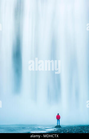 Mann, der an der Basis der Skogafoss Wasserfall ; Island Stockfoto