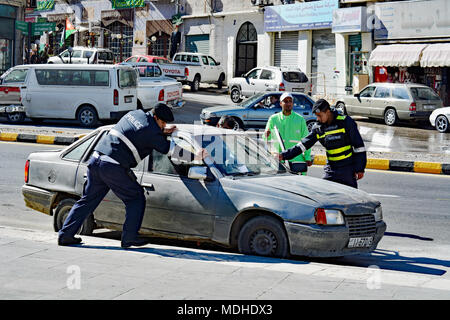 Amman Polizei helfen ein Kraftfahrer mit dem Auto Schwierigkeiten. Ein Verschieben der Straßen vor eine Parade in Amman, Jordanien zu löschen. Stockfoto