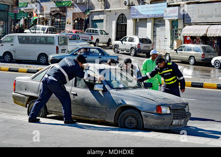 Amman Polizei helfen ein Kraftfahrer mit dem Auto Schwierigkeiten. Ein Verschieben der Straßen vor eine Parade in Amman, Jordanien zu löschen. Stockfoto