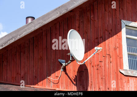 Satellitenschüssel montiert auf der hölzernen Wand des Hauses Stockfoto