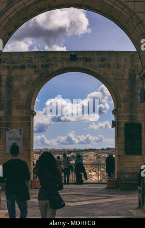 Valletta, Malta, Upper Barrakka Gardens. Terrasse mit Steinbögen und ein Blick auf den Grand Harbour, bewölkt blauer Himmel. Stockfoto