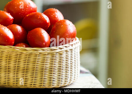 Frische rote Tomaten mit Wassertropfen auf es in einer rustikalen Korb, negativen Raum Stockfoto