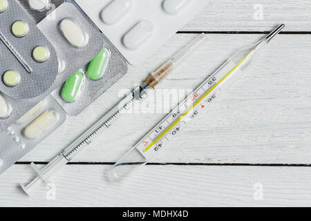 Satz von Tabletten, Kapseln im Blister, Spritze, Thermometer auf Holzuntergrund mit Platz kopieren. Medizin Konzept. Stockfoto