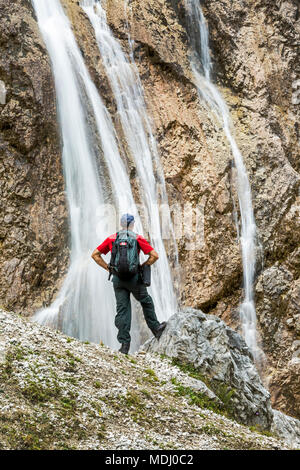 Männliche Wanderer auf felsigen Hang mit Blick auf die Klippen Wasserfälle; Grainau, Bayern, Deutschland Stockfoto