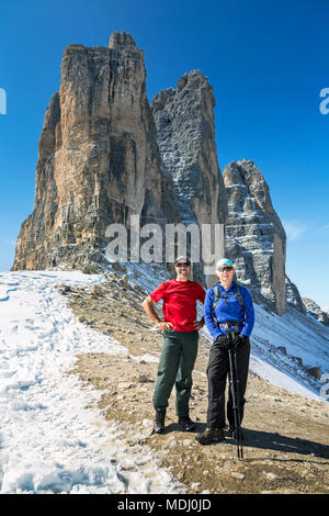 Männliche und weibliche Wanderer stehen auf felsigen Hang mit dramatischen Berg Turmspitzen und blauen Himmel; Sesto, Bozen, Italien Stockfoto