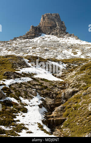 Berg über einem schneebedeckten Hang mit kleinen Bach hinunter fließen und blauen Himmel; Sesto, Bozen, Italien Stockfoto