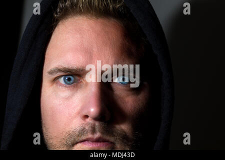 Nahaufnahme Gesicht portrait von Mitte nach kaukasischer Mann mit markanten stechenden blauen Augen vor einem dunklen Hintergrund Model Release: Ja. Property Release: Nein. Stockfoto