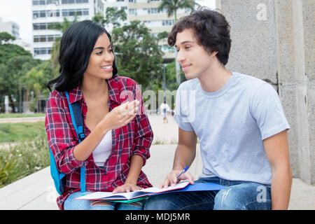 Native lateinamerikanischen Studentin in der Diskussion mit den kaukasischen Freund draußen auf dem Campus der Universität Stockfoto