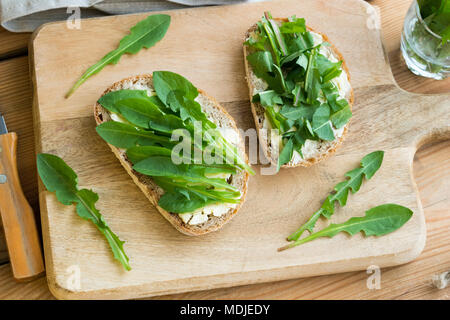 Zwei Scheiben Sauerteig Brot mit Butter und frischem Löwenzahn Blätter Stockfoto