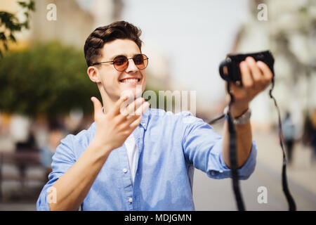 Stattliche Tourist, der eine selfie. Junge Mann an der Kamera in einem städtischen Szene lächelnd. Kaukasischen Völker. Konzept über Leute, Lifestyle und Technologie Stockfoto