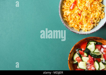 Traditionelle nationale mexikanische Tomaten geschmort Reis Pilav mit Hot Chili Peppers Knoblauch in Türkis Schüssel. Frische Gurke Zwiebel Salsa Salat in Holz- Gericht Stockfoto